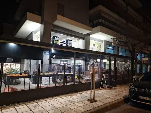Η βιτρίνα του Oliméri φωτισμένη το βράδυ από τον δρόμο
